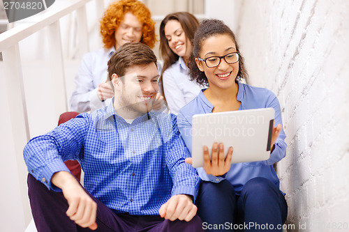 Image of team with tablet pc computer sitting on staircase