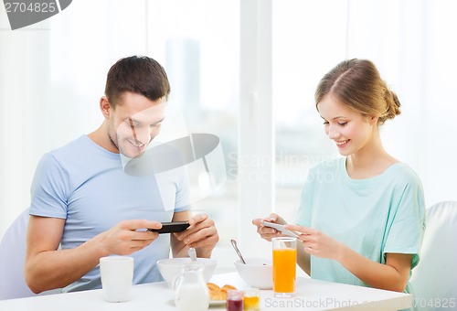 Image of smiling couple with smartphones taking picture