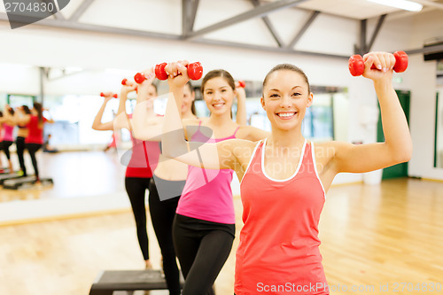 Image of group of smiling female with dumbbells and step