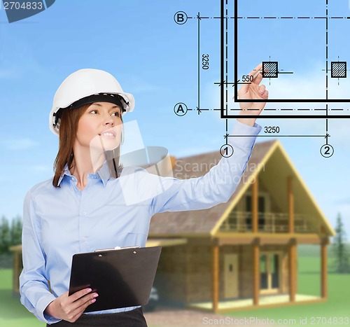 Image of smiling businesswoman in helmet with clipboard