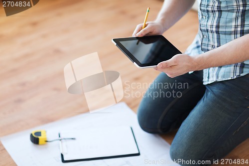 Image of male with tablet pc, blueprint and measuring tape