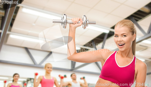 Image of smiling woman with heavy steel dumbbell