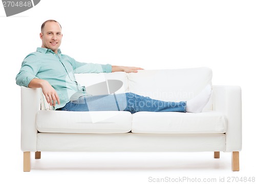 Image of smiling man lying on sofa