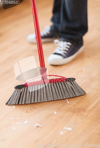 Image of close up of male brooming wooden floor