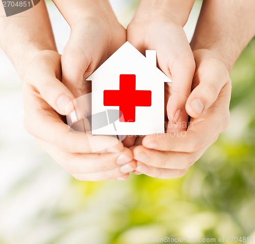 Image of hands holding paper house with red cross