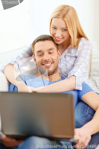 Image of smiling happy couple with laptop at home