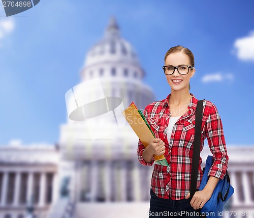 Image of female student in eyeglasses with bag and folders