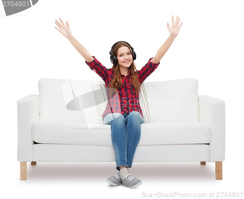 Image of teenage girl sitting on sofa with headphones