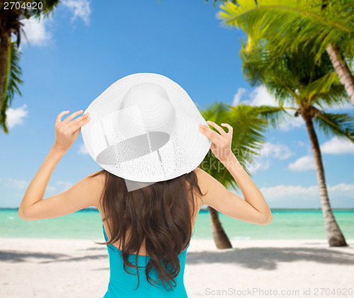 Image of woman sitting in swimsuit with hat