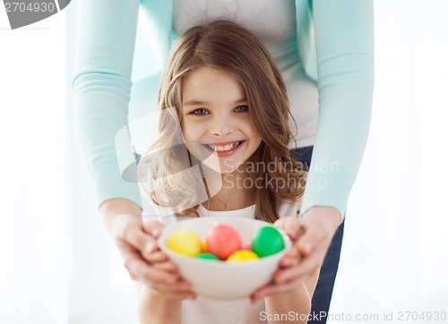 Image of smiling girl and mother holding colored eggs