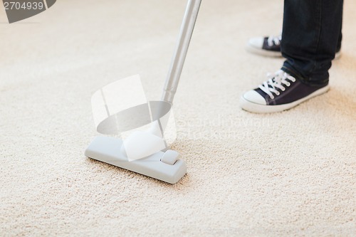 Image of close up of male hoovering carpet