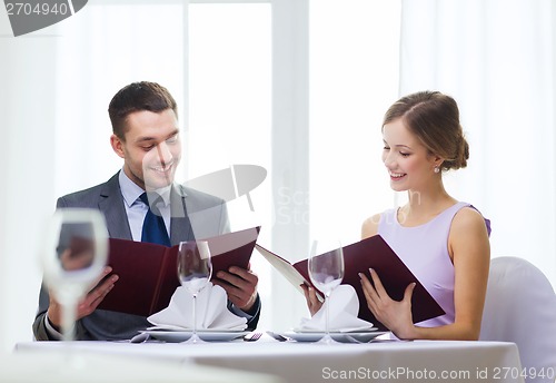 Image of smiling couple with menus at restaurant