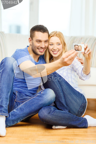 Image of smiling couple taking picture with digital camera