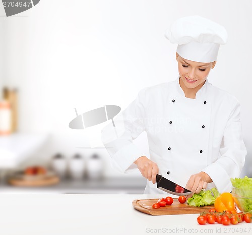 Image of smiling female chef chopping vagetables