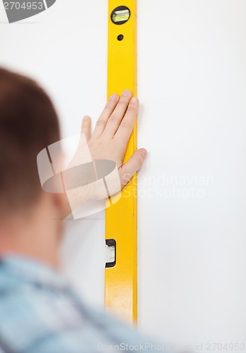 Image of close up of male with spirit level mesuring wall