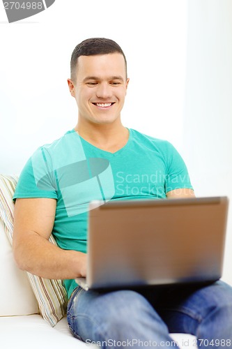 Image of smiling man working with laptop at home