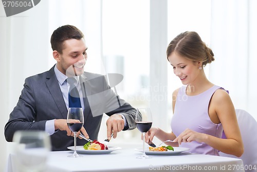 Image of smiling couple eating main course at restaurant