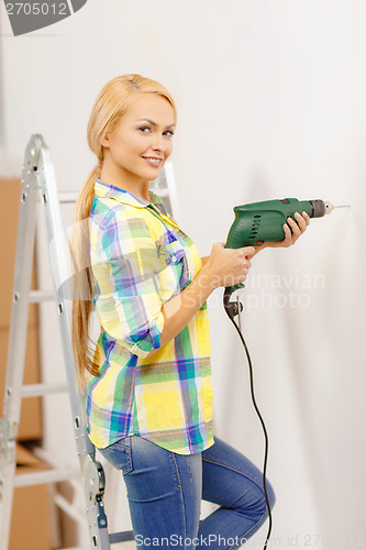 Image of woman with electric drill making hole in wall