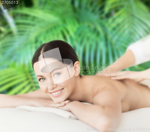Image of smiling woman in spa salon getting massage