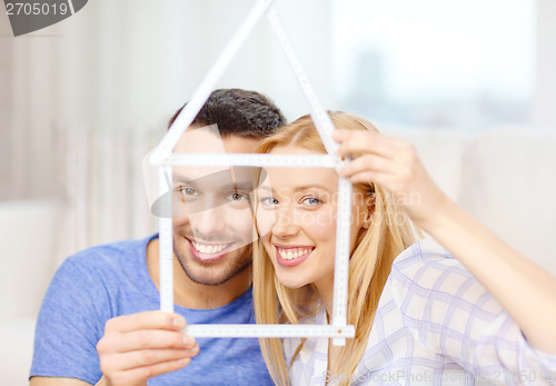 Image of smiling couple with house from measuring tape