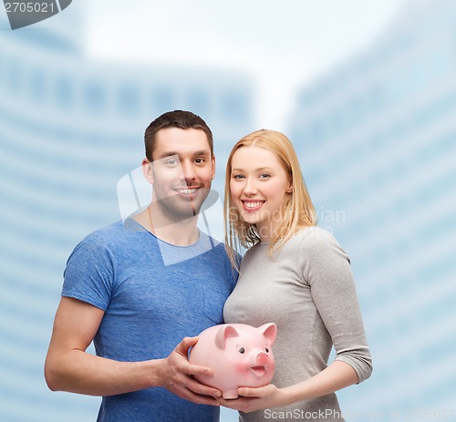 Image of smiling couple holding big piggy bank