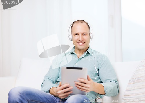 Image of smiling man with tablet pc and headphones at home