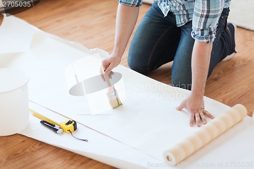 Image of closeup of male hands smearing wallpaper with glue