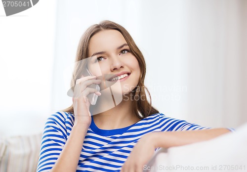 Image of smiling teenage girl with smartphone at home