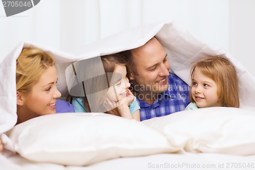 Image of happy family with two kids under blanket at home