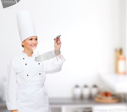 Image of smiling female chef writing something on air