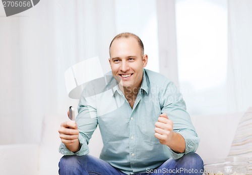 Image of smiling man watching sports at home