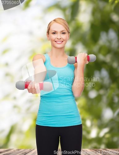 Image of young sporty woman with light dumbbells