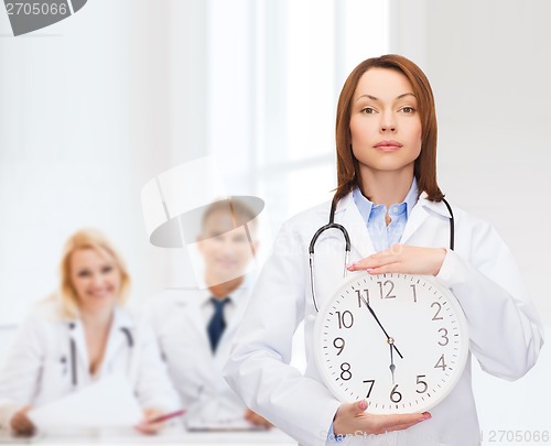 Image of calm female doctor with wall clock