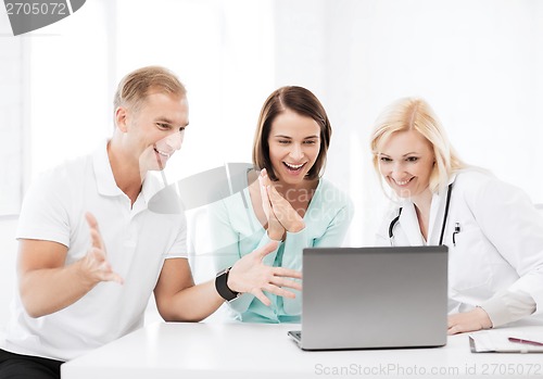 Image of doctor with patients looking at laptop