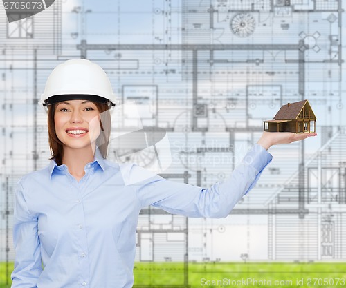 Image of businesswoman in helmet holding house on palm