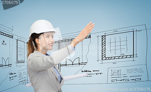 Image of smiling architect in white helmet with blueprints