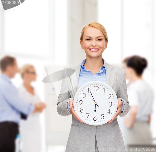 Image of smiling businesswoman with wall clock