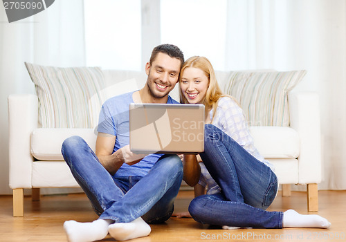 Image of smiling happy couple with laptop at home