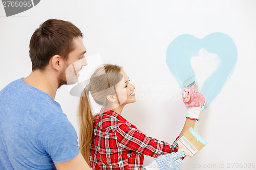 Image of smiling couple painting small heart on wall