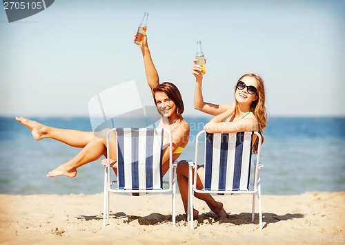 Image of girls sunbathing on the beach chairs