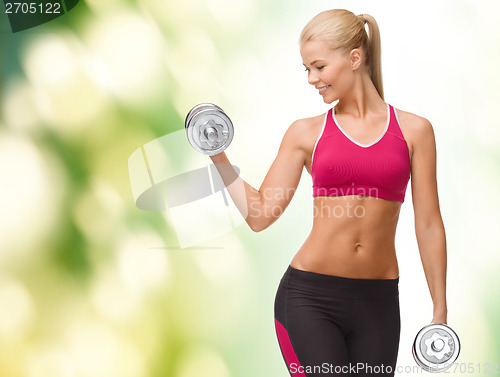 Image of smiling woman lifting steel dumbbell