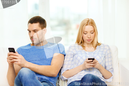 Image of concentrated couple with smartphones at home