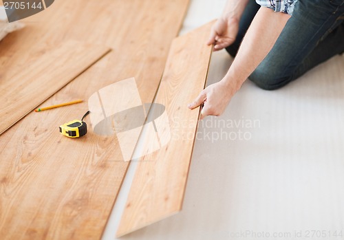 Image of close up of male hands intalling wood flooring