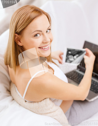 Image of smiling pregnant woman with laptop computer