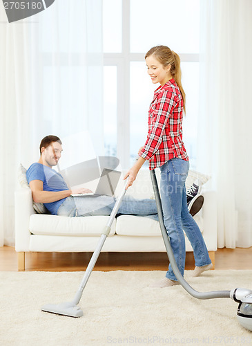 Image of smiling woman with hoover and man with laptop