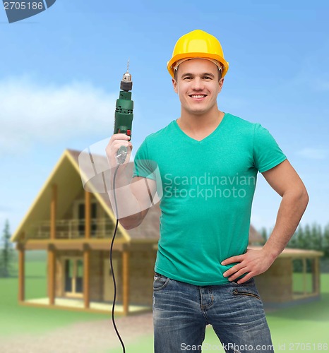 Image of smiling manual worker in helmet with drill machine