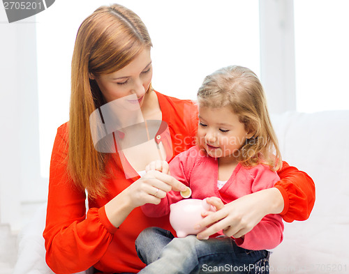 Image of happy mother and daughter with small piggy bank
