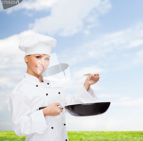 Image of smiling female chef with pan and spoon