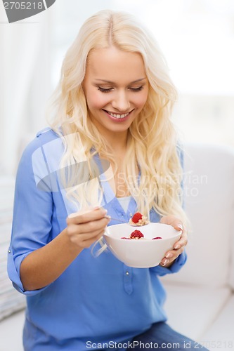 Image of smiling woman with bowl of muesli having breakfast