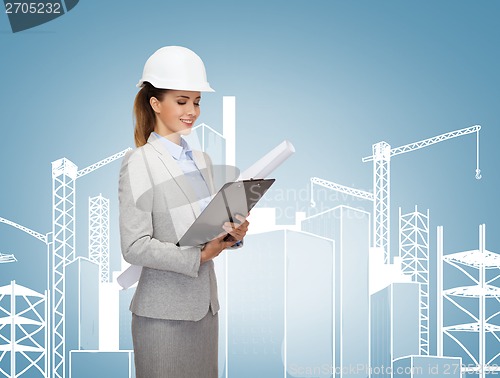 Image of smiling architect in white helmet with blueprints